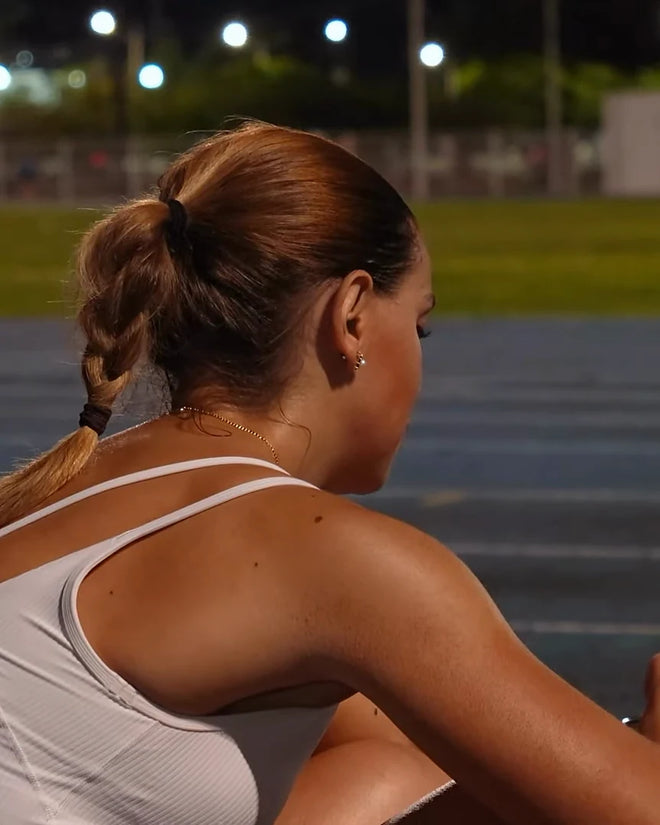 Atleta concentrada sentada en la pista antes de entrenar